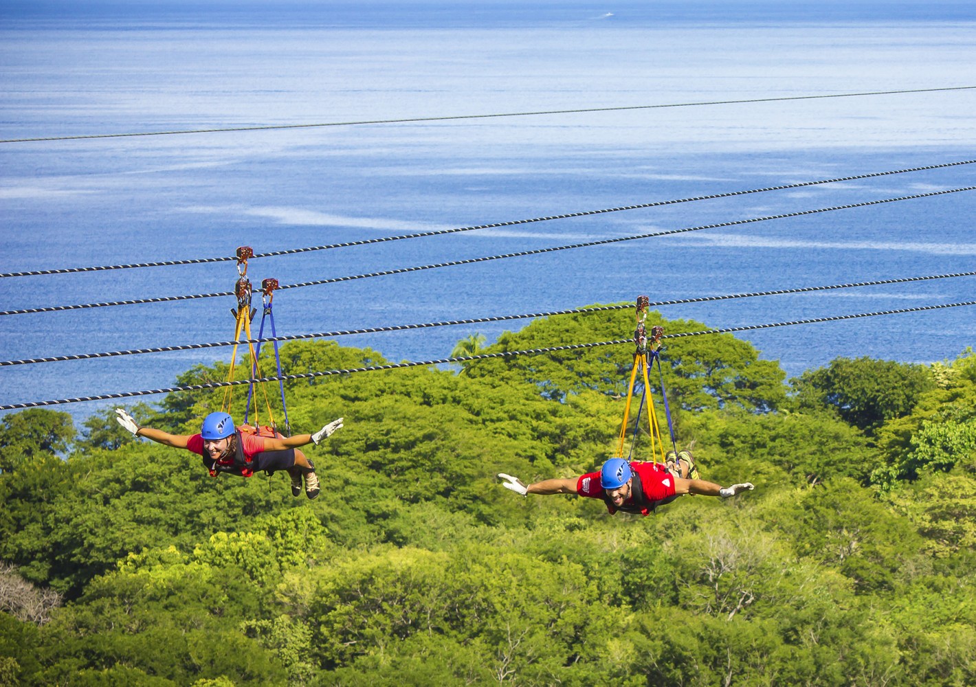 Zipline rider soaring above the ocean-view forest canopy at Diamante Eco Adventure Park in Guanacaste, Costa Rica