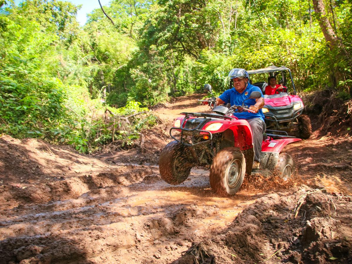 Two men driving an ATV through the jungle