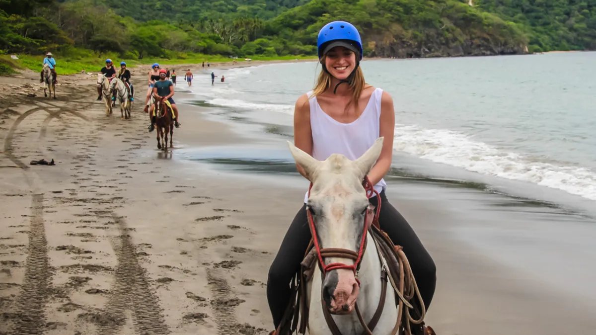 A woman riding a horse on the beach