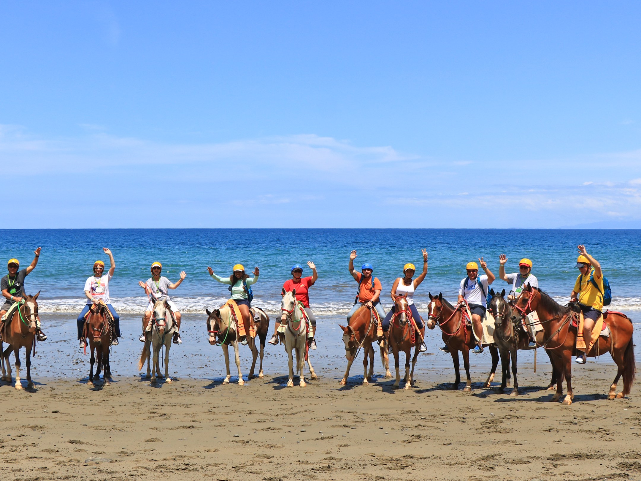 A group of people on the beach riding horses