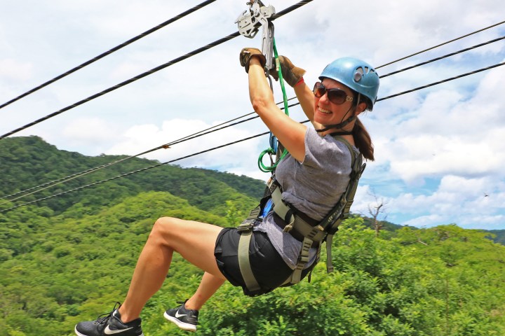 A woman looking at the camera as she ziplines