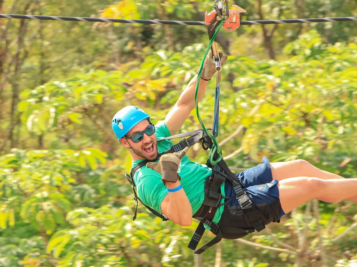 a guy ziplining over a forest