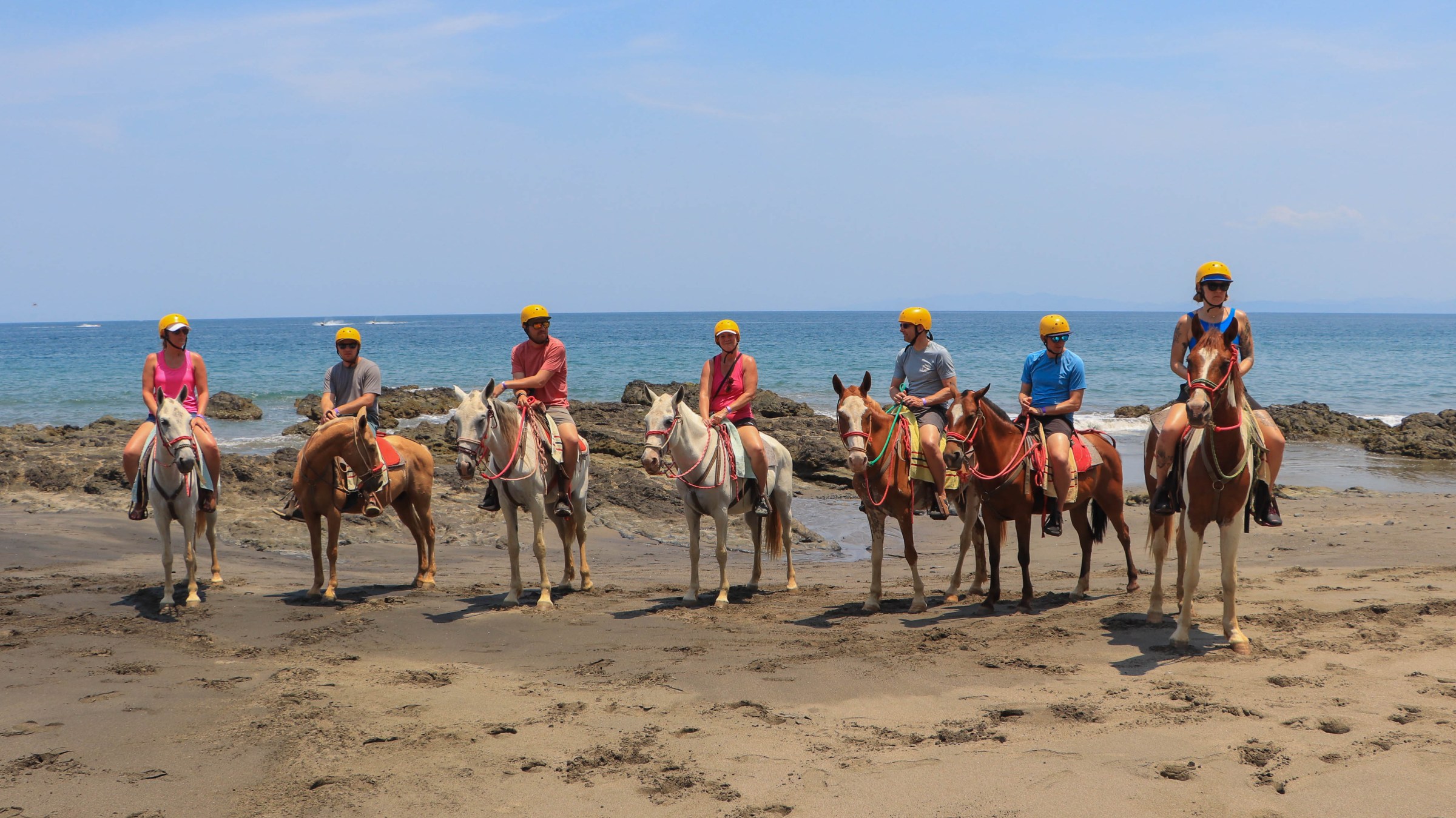 a group of people riding horses on a beach