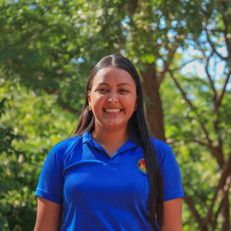 a woman wearing a blue shirt standing in front of a tree