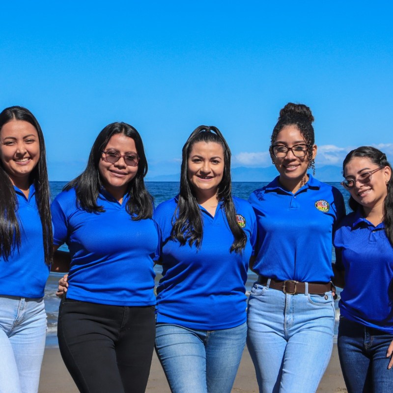 a woman standing next to a body of water posing for the camera