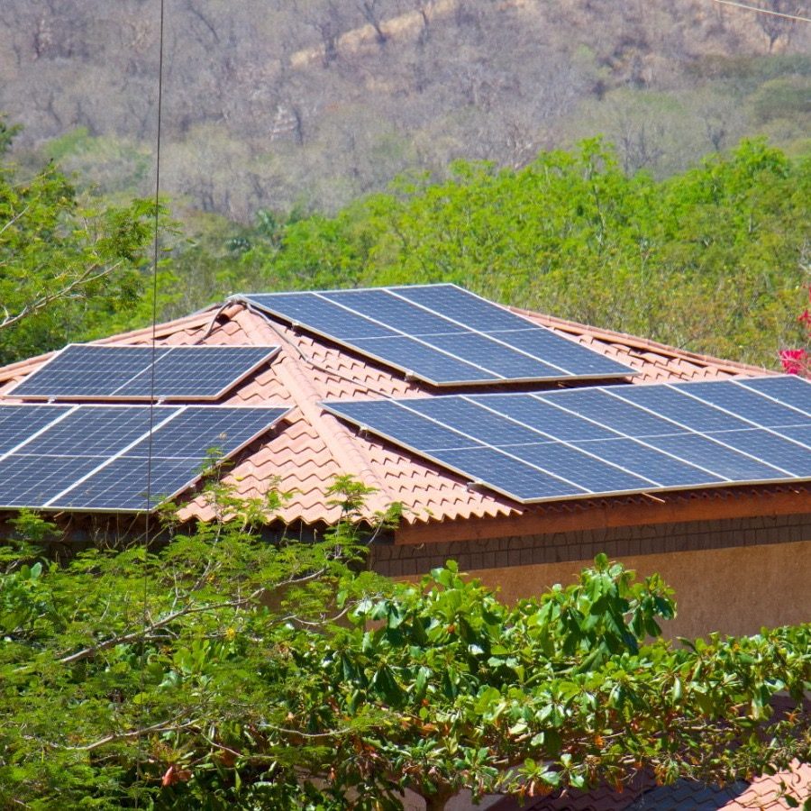 House with solar panels on roof, surrounded by trees and colorful foliage.