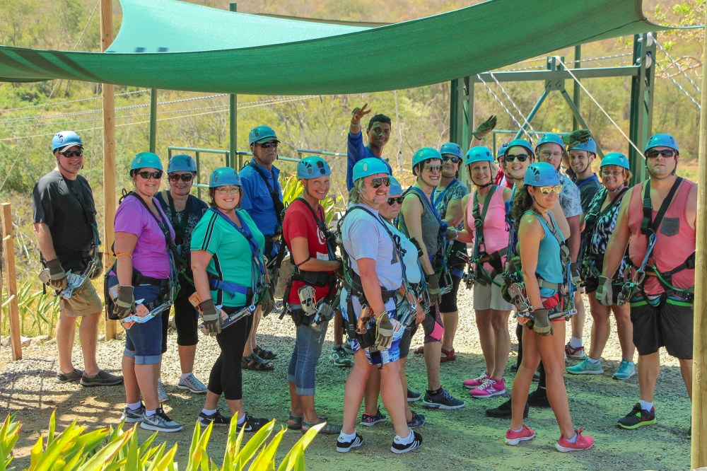 Group of guests geared up in full-body harnesses and helmets before the zip line tour